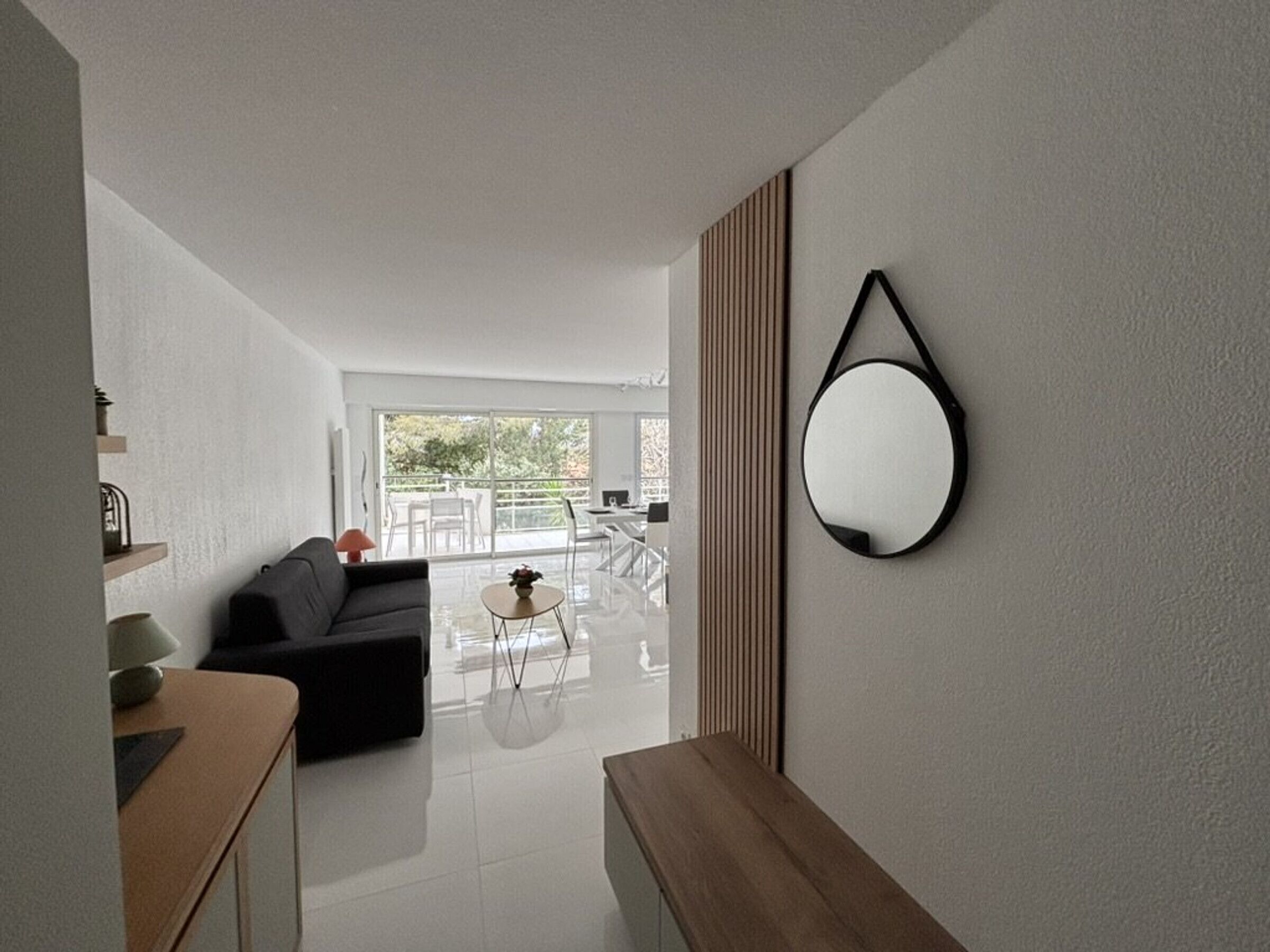 A modern living room with a sofa, coffee table, and a dining area with a table and chairs.