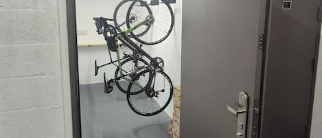 A door with a bicycle rack mounted on the wall, a door handle, and a small sign on the door.