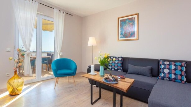 A modern living room with a sofa, a blue armchair, a wooden coffee table, and a painting on the wall.