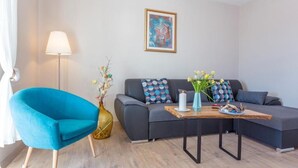 A modern living room with a blue armchair, a grey sofa, a wooden coffee table, and a floor lamp.