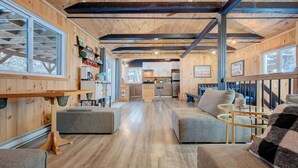 Un intérieur de cabine spacieux avec un plancher en bois, un coin repas doté d’une longue table, une cuisine équipée d’appareils modernes et un salon avec un canapé et une table basse.