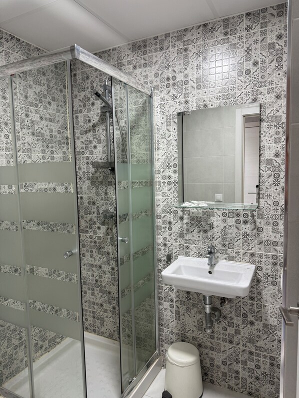Un bagno con doccia, lavandino e specchio.