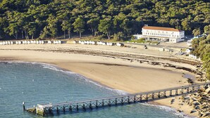 Un paysage côtier avec une plage, une jetée et un bâtiment.