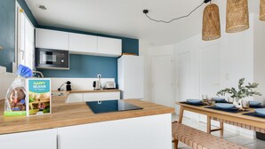Une cuisine moderne avec des armoires blanches, un four à micro-ondes et un plan de travail en bois.