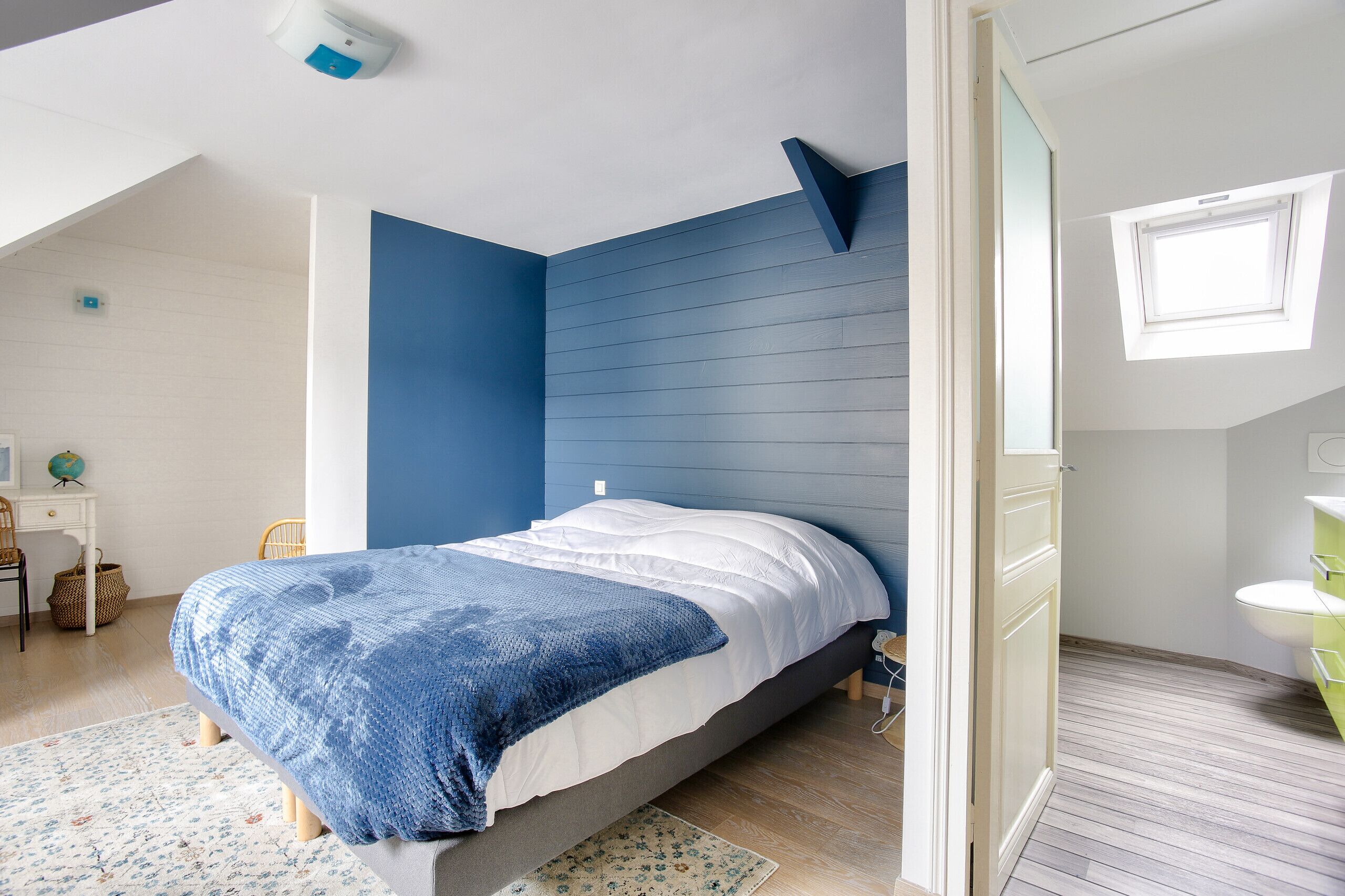 A bedroom with a bed, a desk, and a window.