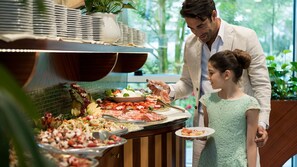 Un buffet proposant une variété de plats et une personne chargée de servir les aliments.