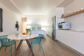 Een moderne keuken met een koelkast, magnetron en oven. Er is een eettafel met stoelen en een klein keukeneiland.