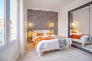 A modern bedroom with two beds, a large mirror, and a city view. - EMILY 2BR 2baths with AC near the Palais (Cannes)