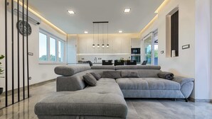 A modern living room with a sectional sofa, a dining area, and a kitchen in the background. - Villa Eva with pool near Medulin (Ližnjan)