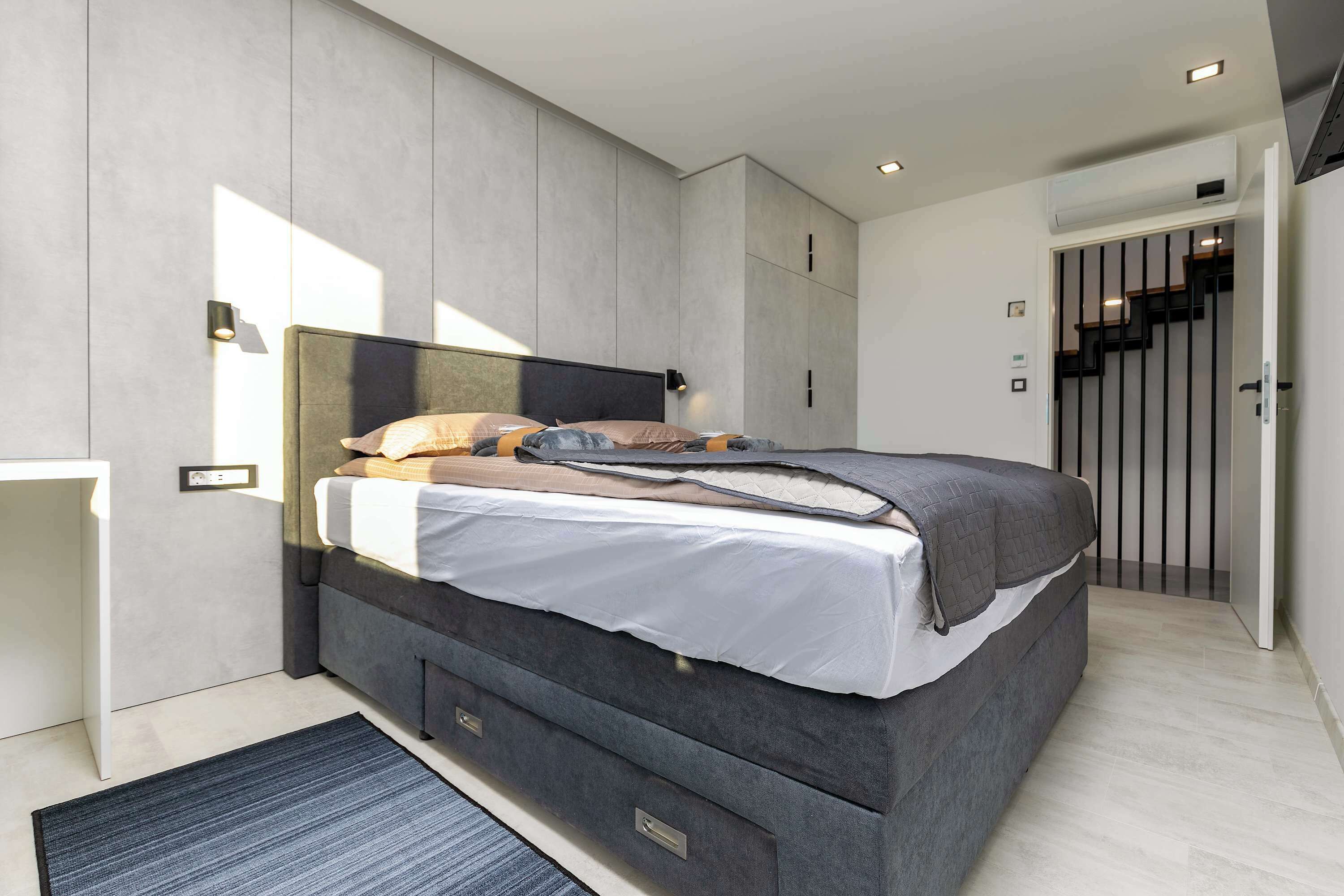 A modern bedroom with a large bed, built-in storage, and a minimalist design.