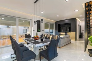 A modern dining area with a white table, black chairs, and a fruit bowl. - Villa Franka with pool near Medulin (Ližnjan)
