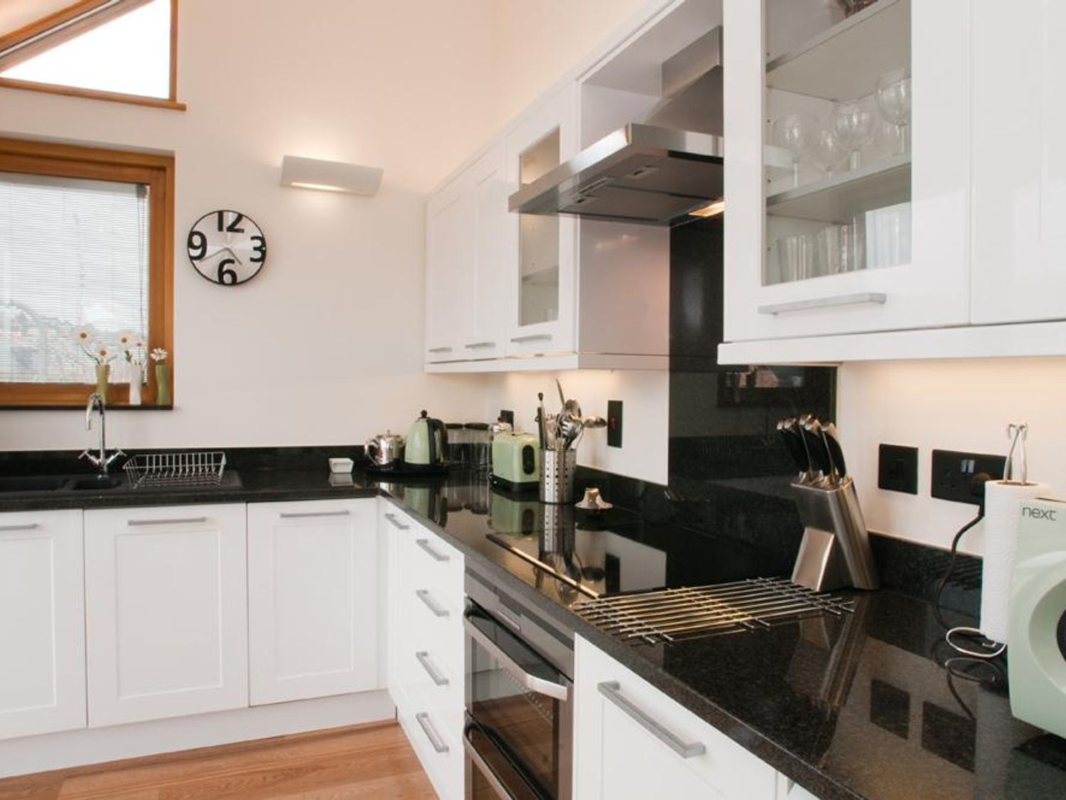A modern kitchen with white cabinets, a black countertop, and a built-in oven.