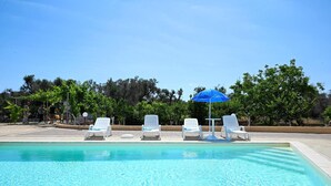 A swimming pool with white lounge chairs and a blue umbrella. - Villa Lino With Pool by Wonderful Italy (San Vito dei Normanni)