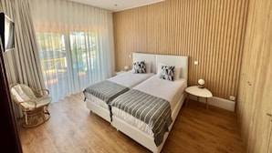 Een moderne slaapkamer met een groot bed, twee nachtkastjes, een stoel en uitzicht op de omgeving.
