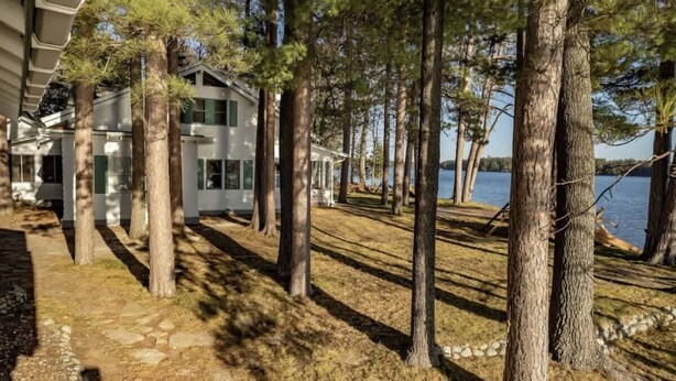 A house with a stone pathway leading to a dock by a lake, surrounded by tall trees. - Pines of Three Lakes (Eagle River)