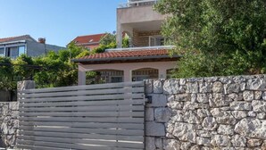 A two-story building with a stone wall and a wooden gate. - Appartamento Nomads Ac Wifi Hvar (Hvar)