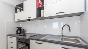 A modern kitchen with white cabinets, a built-in oven, a coffee maker, and a sink. - Appartamento Nomads Ac Wifi Hvar (Hvar)