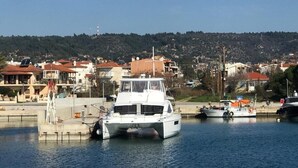 Uma marina com barcos atracados, céu claro e edifícios ao fundo.
