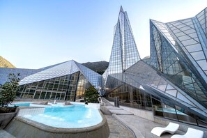 A modern hotel with a pool area, featuring glass facades and contemporary architecture.