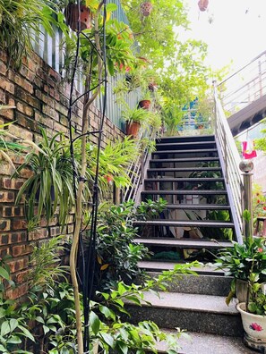 Eine Treppe, umgeben von üppigem Grün und Blumentöpfen, die zu einer höheren Ebene führt.