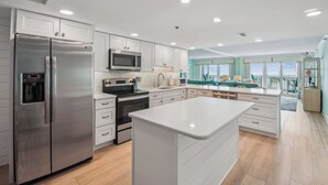 A modern kitchen with stainless steel appliances, white cabinetry, and a large island.