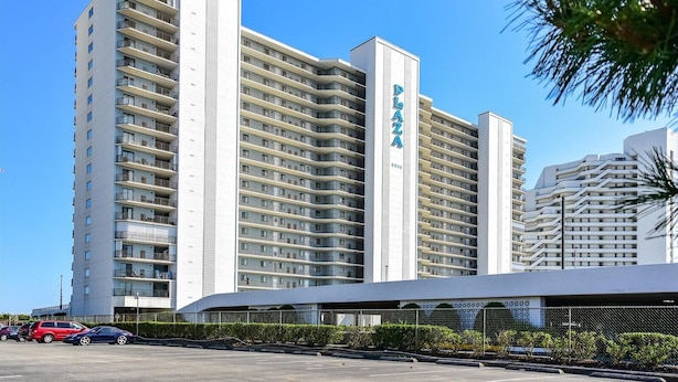Un hotel de gran altura con varios balcones, un letrero destacado que dice 'Palo Alto' y un área de estacionamiento al frente.