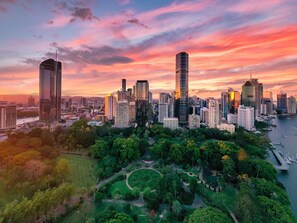 A cityscape with high-rise buildings, a park with a circular garden, and a body of water.