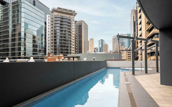 A rooftop pool with a cityscape view, surrounded by modern buildings.