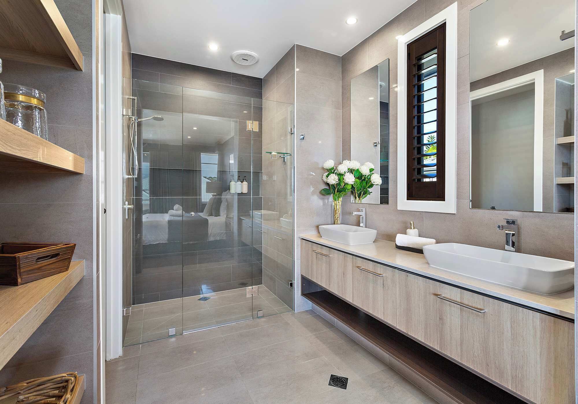A modern bathroom with a glass shower enclosure, two sinks, and wooden cabinetry.