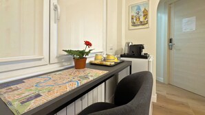 A kitchen area with a map on the counter, a potted plant with a red flower, and a coffee machine. - Vatican Dolce Remy Guest House (Rome)