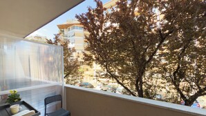 A balcony with a chair and a small table, overlooking a tree and buildings. - Vatican Dolce Remy Guest House (Rome)