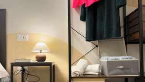 A neatly organized hotel room with a bed, a bedside table with a lamp, a storage box, and a folded towel. - Vatican Dolce Remy Guest House (Rome)