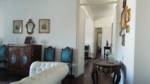 A room with a white leather sofa, a wooden cabinet with decorative mirrors, and a small round table with a vase. - Apartment 3bedr 2bathr,FreeParking,CITY CENTER, Cosy and Chic, SEA VIEW (Palermo)