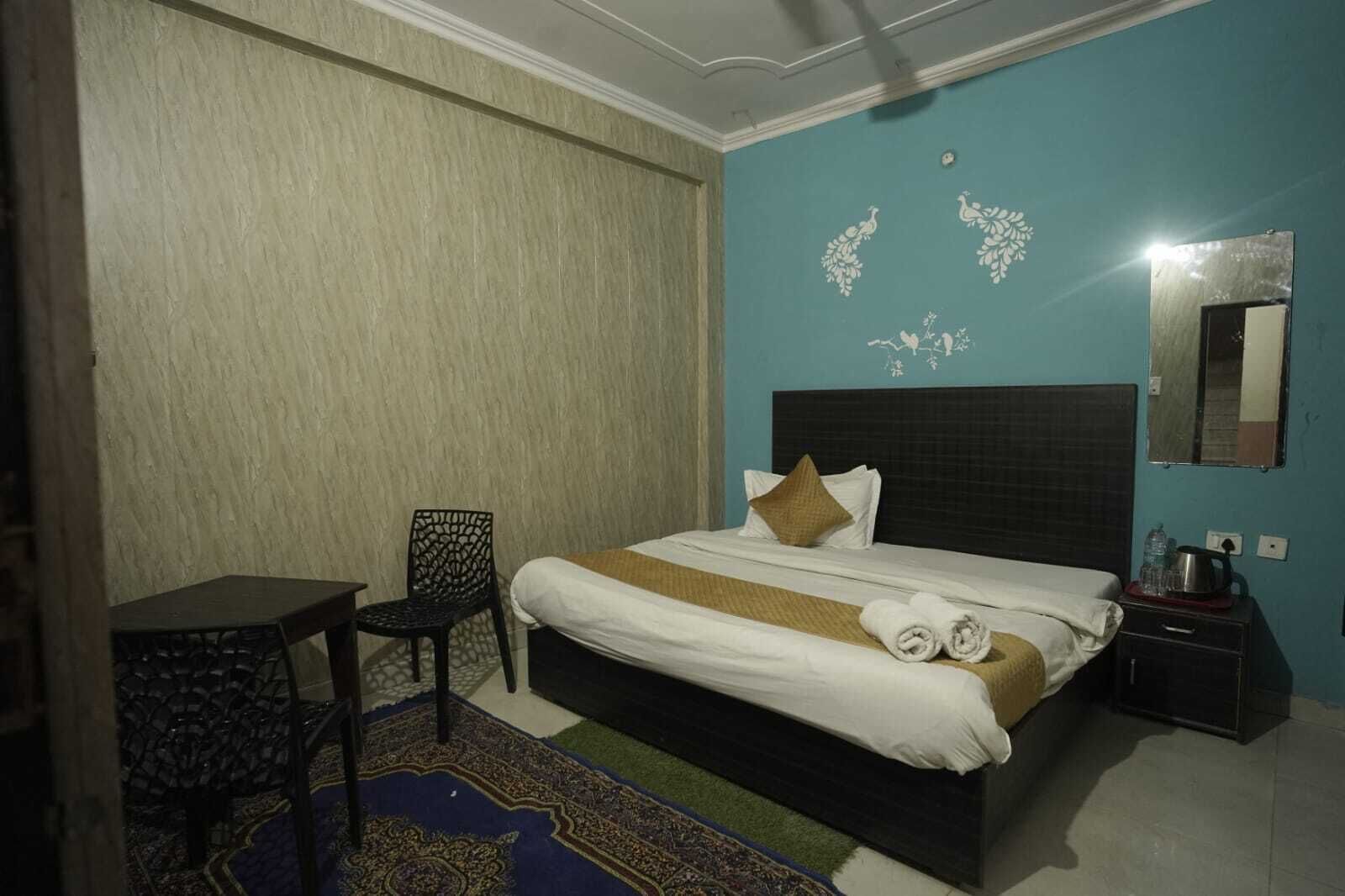 Een hotelkamer met een bed, een stoel, een nachtkastje en een spiegel.
