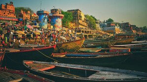 A busy riverside with boats docked and people gathered around. - Om Sai guest house (Varanasi)