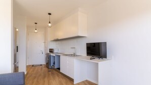 Una cocina moderna con armarios blancos, horno empotrado, microondas y un televisor de pantalla plana grande.
