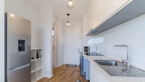 Una cocina moderna con un refrigerador de acero inoxidable, un microondas y un lavamanos con grifo.