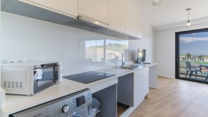 Una cocina moderna con horno empotrado, microondas y lavadora.