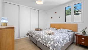 Une chambre à coucher avec un lit, une table de chevet, une lampe et une fenêtre.