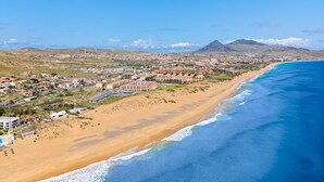 Une ville côtière avec une plage, des bâtiments et une montagne en arrière-plan.