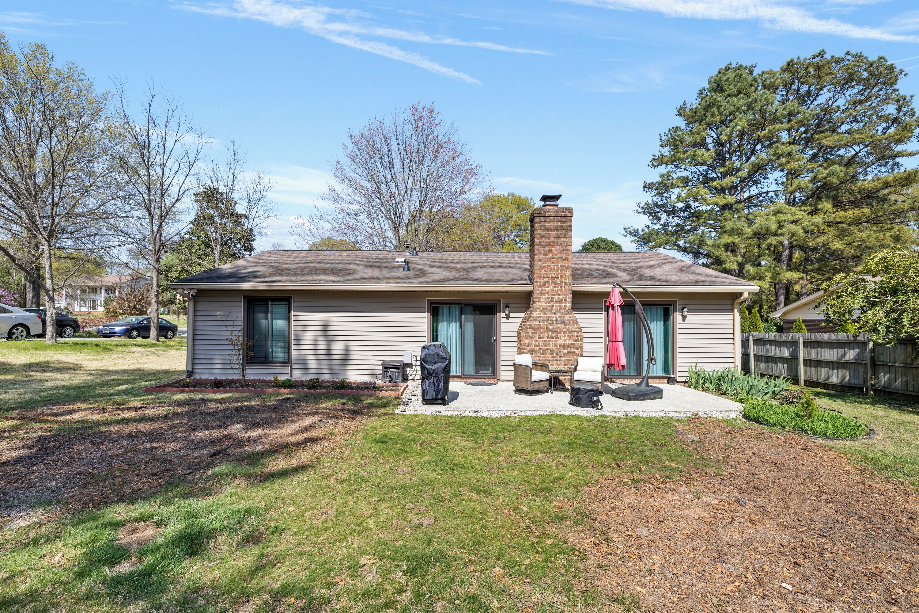 A residential house with a chimney, a patio with outdoor furniture, and a well-maintained lawn.