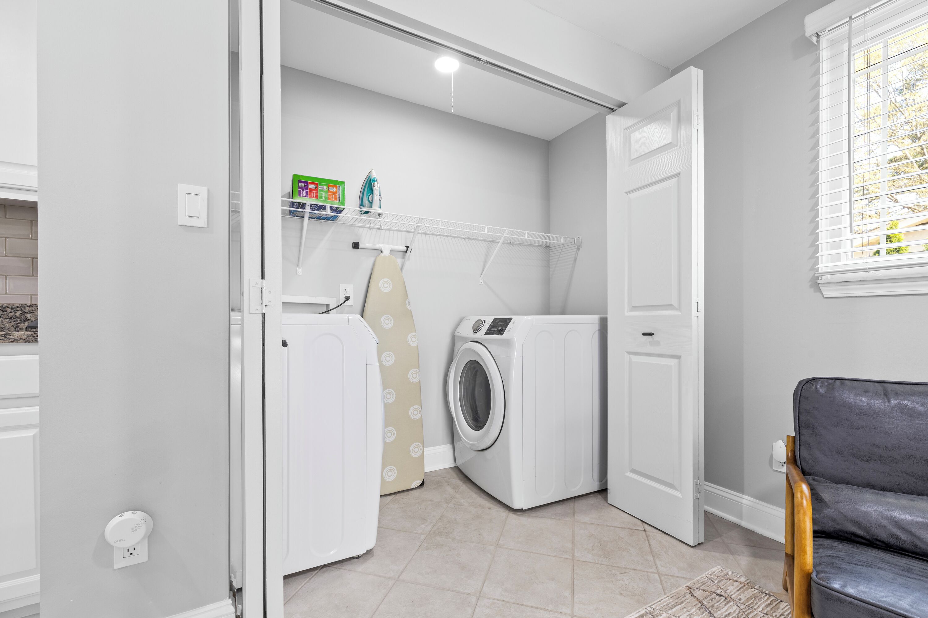 Une buanderie équipée d’un lave-linge, d’un sèche-linge et d’une planche à repasser.