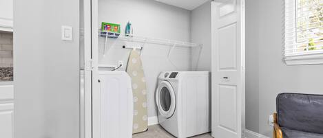 Une buanderie équipée d’un lave-linge, d’un sèche-linge et d’une planche à repasser.