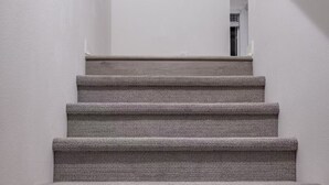 A staircase with a textured carpet, a white wall, and a framed picture of a bird on the wall. - Modern Designer Stay Bright Chic Spacious (Ontario)