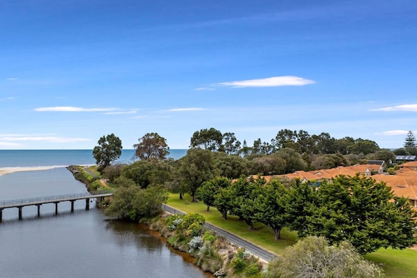 A coastal landscape with a bridge, trees, and buildings with red roofs. - Ocean Breeze Villa - Close to Town and the Beach (West Busselton)