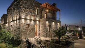 A stone house with a wooden balcony and a well-lit entrance. - Turtulli Castle Stone Villa 1 - Private Pool Oasis (Hersonissos)