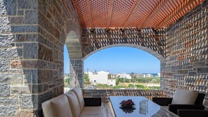 A stone-walled outdoor seating area with a view of the sea and buildings in the distance. - Turtulli Castle Stone Villa 2 - Private Pool Oasis (Hersonissos)