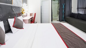 Habitació d'hotel moderna amb un llit gran, un escriptori, una cadira i un sofà.
