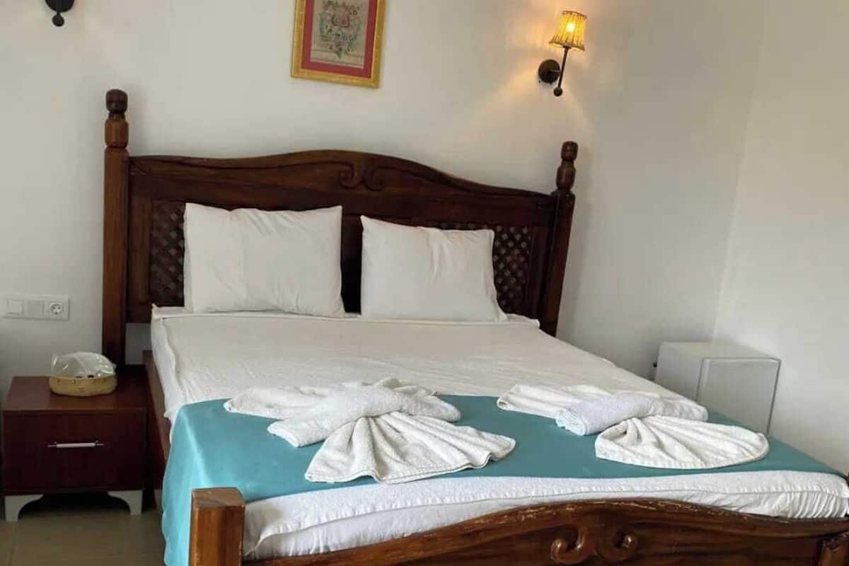 A wooden bed with white linens and towels arranged on the bed.