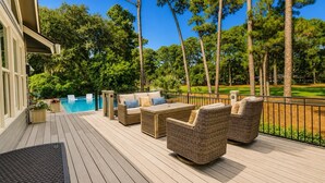 A deck with outdoor furniture, a pool, and a view of a golf course. - 104 Baynard Cove - 11th Tee Box on The Harbour Town Golf Links with Pool. (Hilton Head Island)